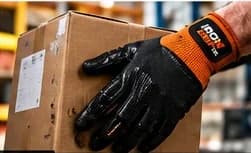 Gloved hand carrying a cardboard box in a warehouse